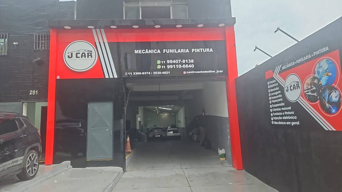 Entrada da Jcar Centro Automotivo, com pórtico vermelho e o letreiro J CAR sobre o portão do galpão.